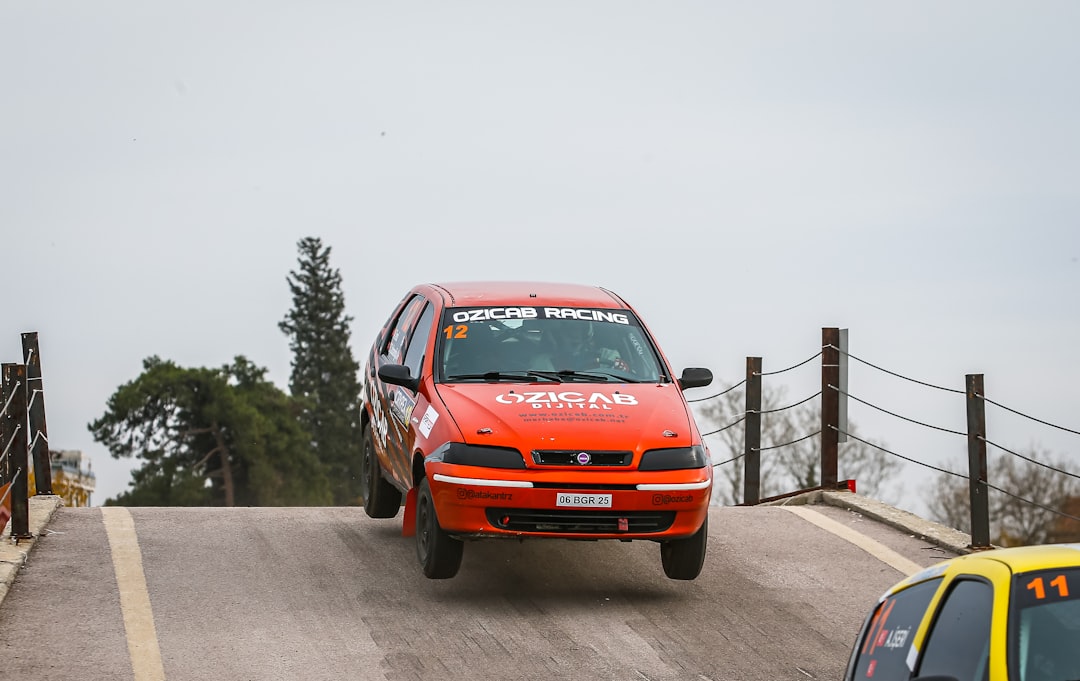 a red car driving down a road next to a yellow car — Foto por Ozicab Racing na Unsplash